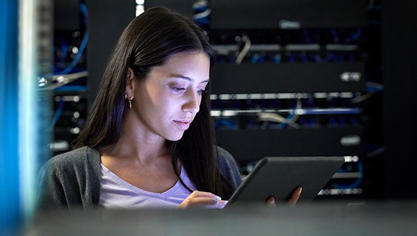 A female engineer working on a tablet in front of a server rack
