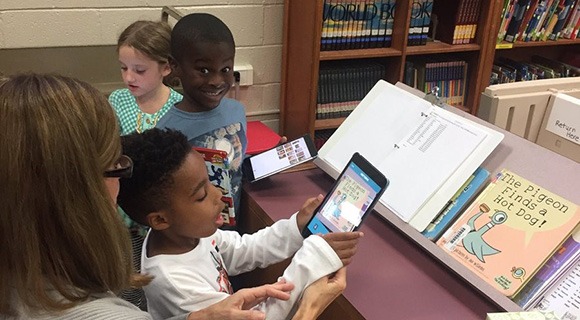 小学生和他们的老师与图书馆的平板电脑互动